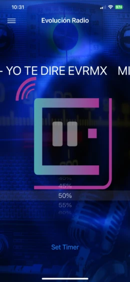 Pantalla de inicio de la aplicación Evolución Radio mostrando opciones de control de volumen.
- **Descripción:** Imagen de la aplicación Evolución Radio, que muestra una interfaz moderna con un logo de pausa en el centro y un fondo azul oscuro. La pantalla incluye un control de volumen que indica el nivel actual y opciones adicionales como "Set Timer". Ideal para descubrir música y programas en línea. Interfaz de aplicación de radio en línea con logo de pausa y niveles de volumen.- **Título:** Evolución Radio App - Interfaz de Usuario- **Leyenda:** Pantalla de inicio de la aplicación Evolución Radio mostrando opciones de control de volumen.- **Descripción:** Imagen de la aplicación Evolución Radio, que muestra una interfaz moderna con un logo de pausa en el centro y un fondo azul oscuro. La pantalla incluye un control de volumen que indica el nivel actual y opciones adicionales como